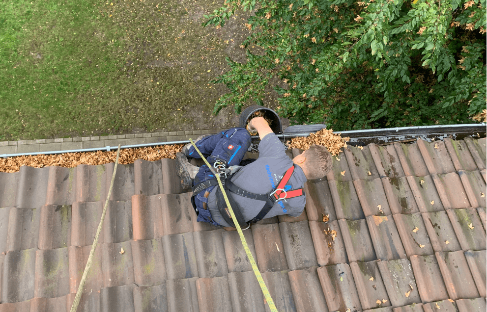 Mann bei Dachrinnenreinigung auf Dach